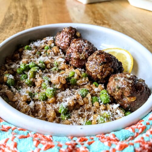 A side view of 4 baked meatballs, served with lemon and mint barley risotto.