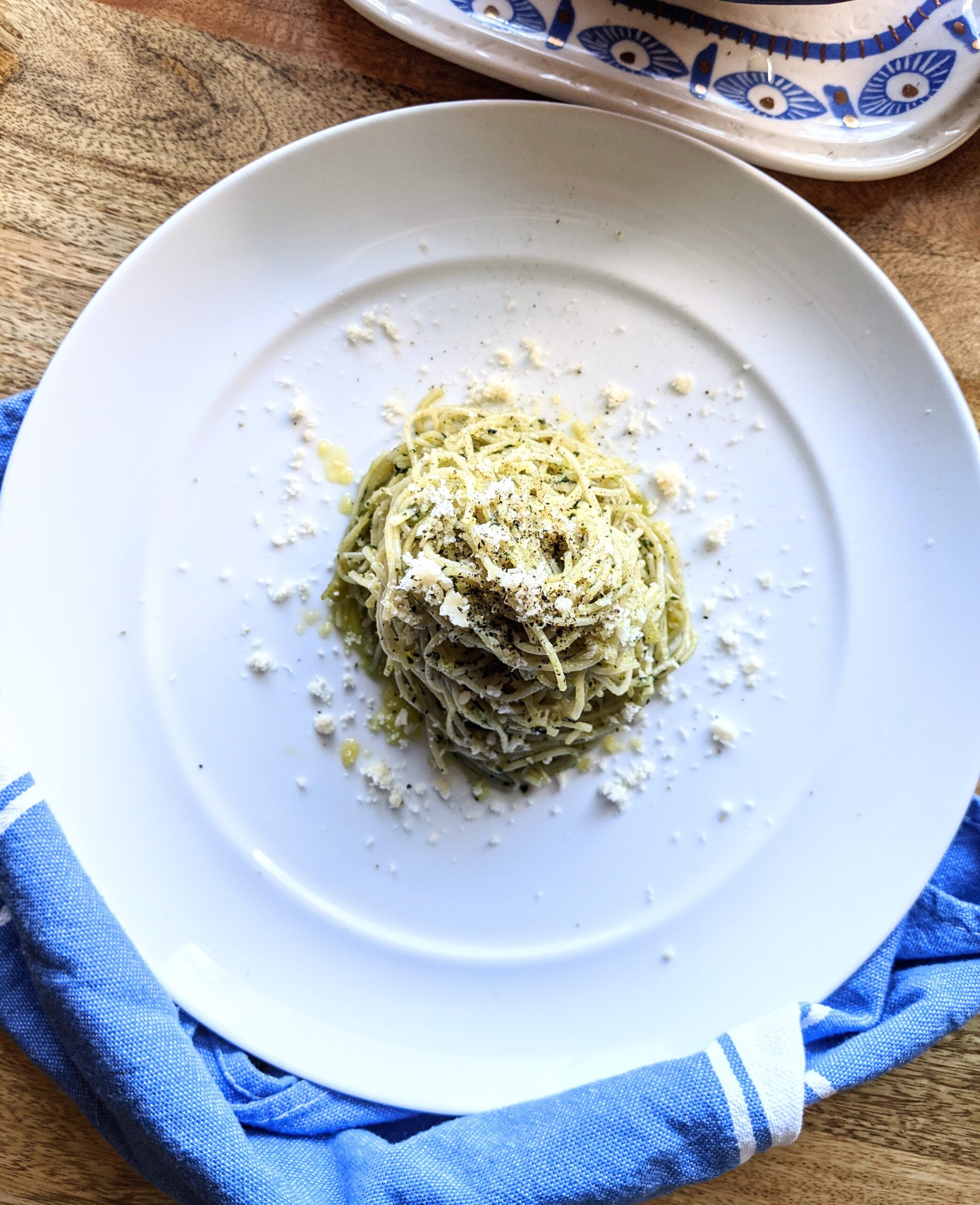 Herbaceous fresh basil pesto tossed with al dente spaghetti and then twisted into a little nest in the center of a large white plate. Garnished with heaps of freshly grated Parmigiano Reggiano.