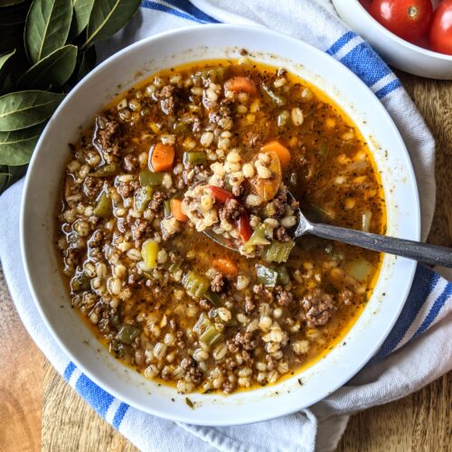 A bowl of satisfying Beef and Barley Soup, made with ground beef. Carrots, celery, and green bell pepper mix with Italian barley and a variety of fresh & dried herbs.