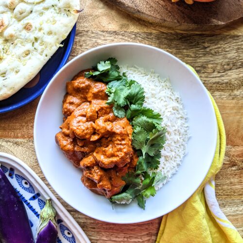 A bowl of rich tomato based butter chicken. Serve over basmati rice and alongside warm naan bread. Garnished with a generous amount of fresh cilantro.