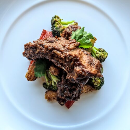 Two large Cambodian-style ribs with cognac and cinnamon, perched on top sautéed baby corn, red bell pepper, and broccoli.