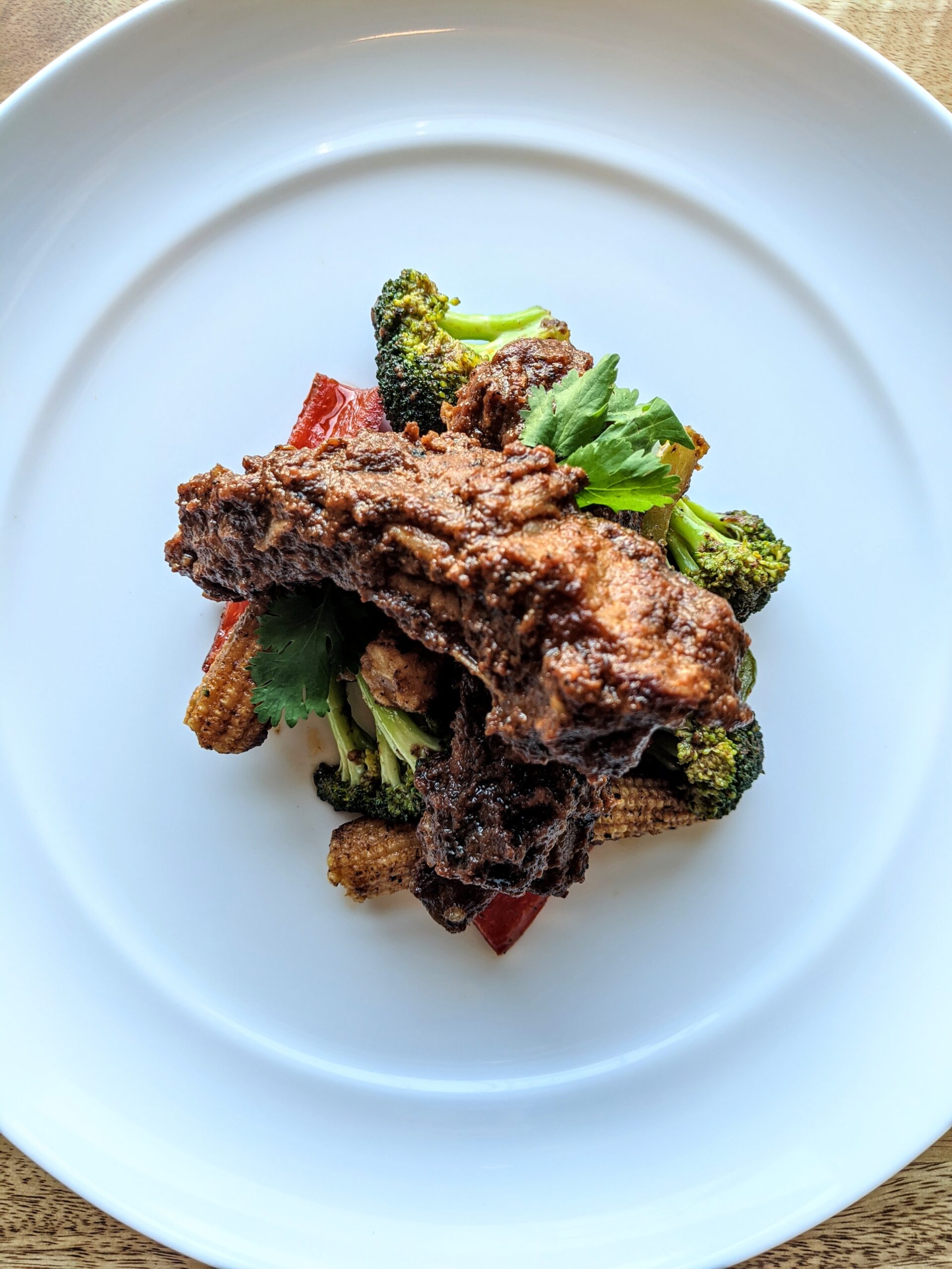 Two large Cambodian-style ribs with cognac and cinnamon, perched on top sautéed baby corn, red bell pepper, and broccoli.
