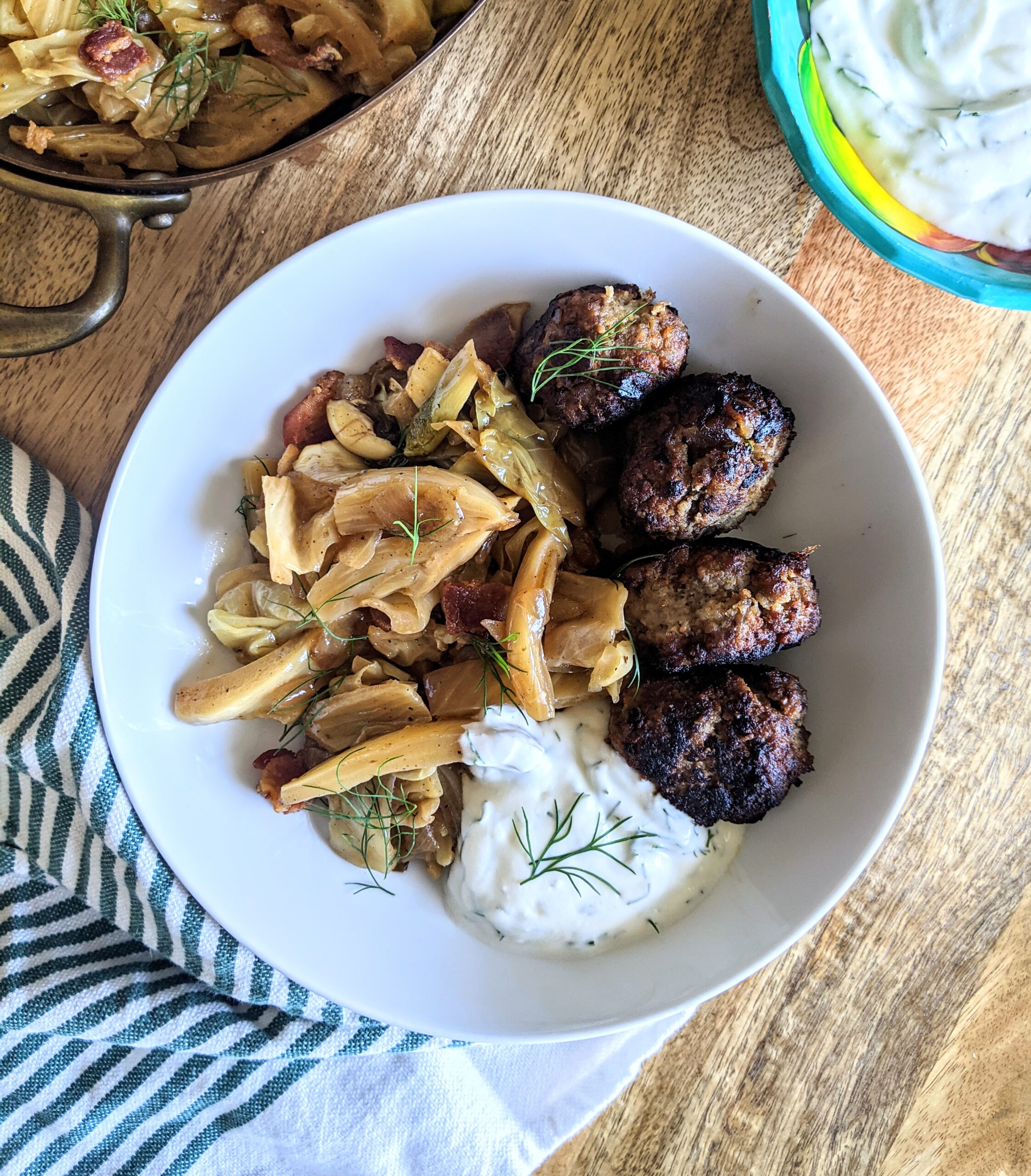Four pan-fried meatballs stuffed with sweet sun-dried dates from summertime and tart apples. Served alongside apple cider vinegar braised cabbage and fennel, and a yogurt and dill sauce.