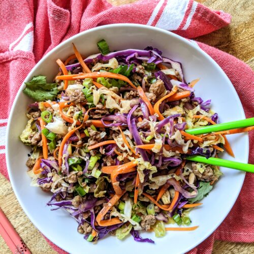 An inside out egg roll in a bowl, no deep frying involved! Shredded purple cabbage, green cabbage, and carrots, tossed with browned ground pork and all the flavors reminiscent of traditional egg rolls.