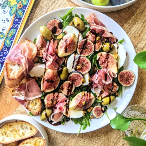 A family-style salad made of sliced and quartered Mission and Tiger Figs, thick slices of fresh Mozzarella, ripples of Italian prosciutto, Cerignola olives, lightly dressed wild arugula, and chili olive oil crostini.
