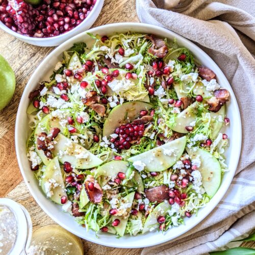 A salad of bitter frisée, pieces of crispy smoked bacon, sliced tart apple, sweet pomegranate arils, tangy feta, with simple apple cider vinaigrette