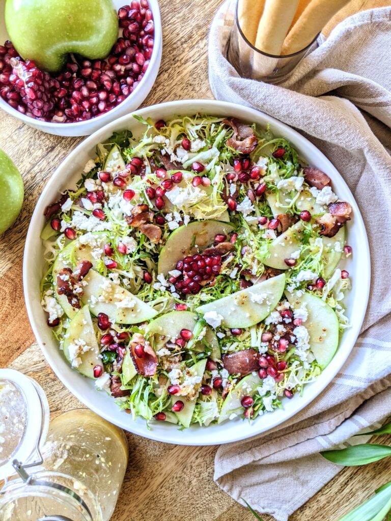 A salad of bitter frisée, pieces of crispy smoked bacon, sliced tart apple, sweet pomegranate arils, tangy feta, with simple apple cider vinaigrette