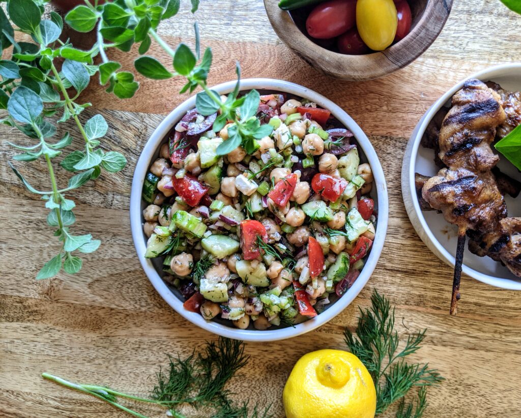 Greek chickpea salad with tomatoes, Persian cucumbers, red onion, feta, and fresh oregano & dill. Served alongside jerk chicken skewers.