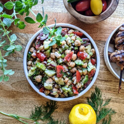 Greek chickpea salad with tomatoes, Persian cucumbers, red onion, feta, and fresh oregano & dill. Served alongside jerk chicken skewers.