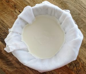 Whole milk yogurt straining in a few layers of cheesecloth.