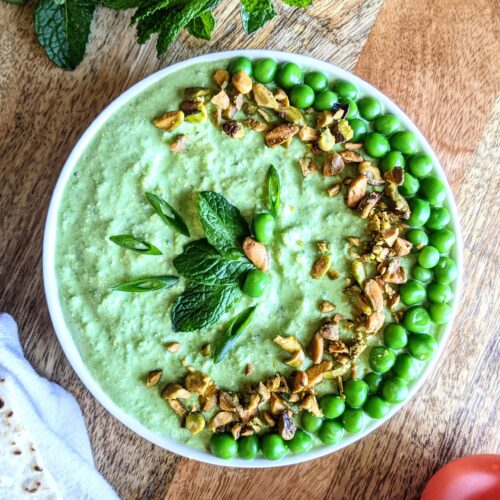 A bright green dip make of sweet spring peas and salty feta. Garnished with chopped roasted pistachios and whole steamed peas arranged in the shape of a crescent moon, and a few leaves of fresh mint.