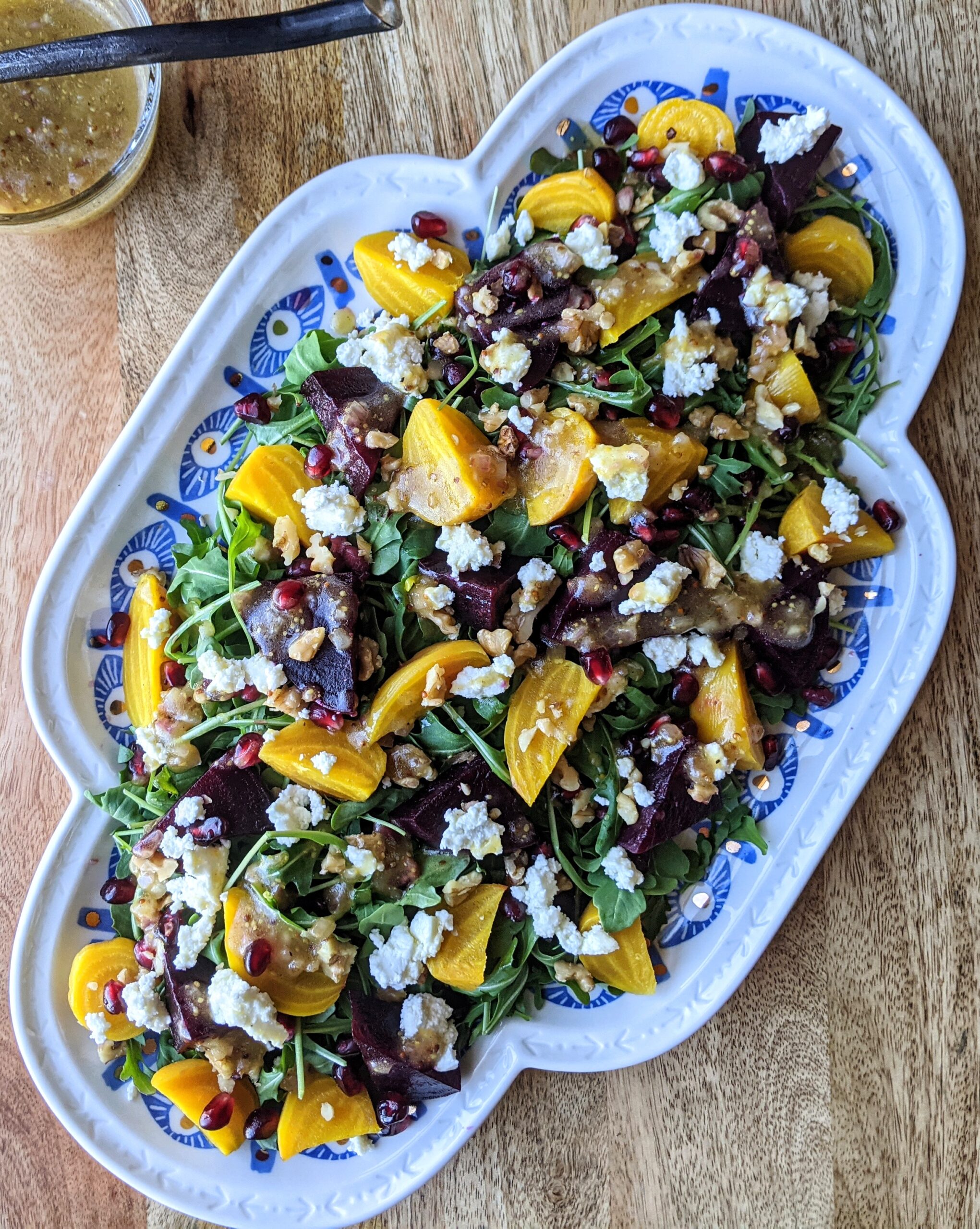 Roasted golden and purple beet salad with arugula, goat cheese, walnuts, and pomegranate arils. Served family-style on a large platter.