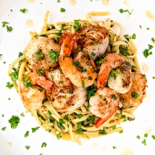 A nest of al denta spaghetti topped with an abundance of seared scallops and shrimp. Garnished with a generous sprinkle of chopped Italian parsley and a drizzle of extra-virgin olive oil.