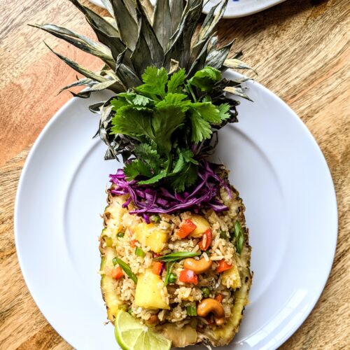 Authentic Thai-style pineapple fried rice served in a hollowed out pineapple. Topped with toasted cashews, fresh cilantro, and raw purple cabbage.
