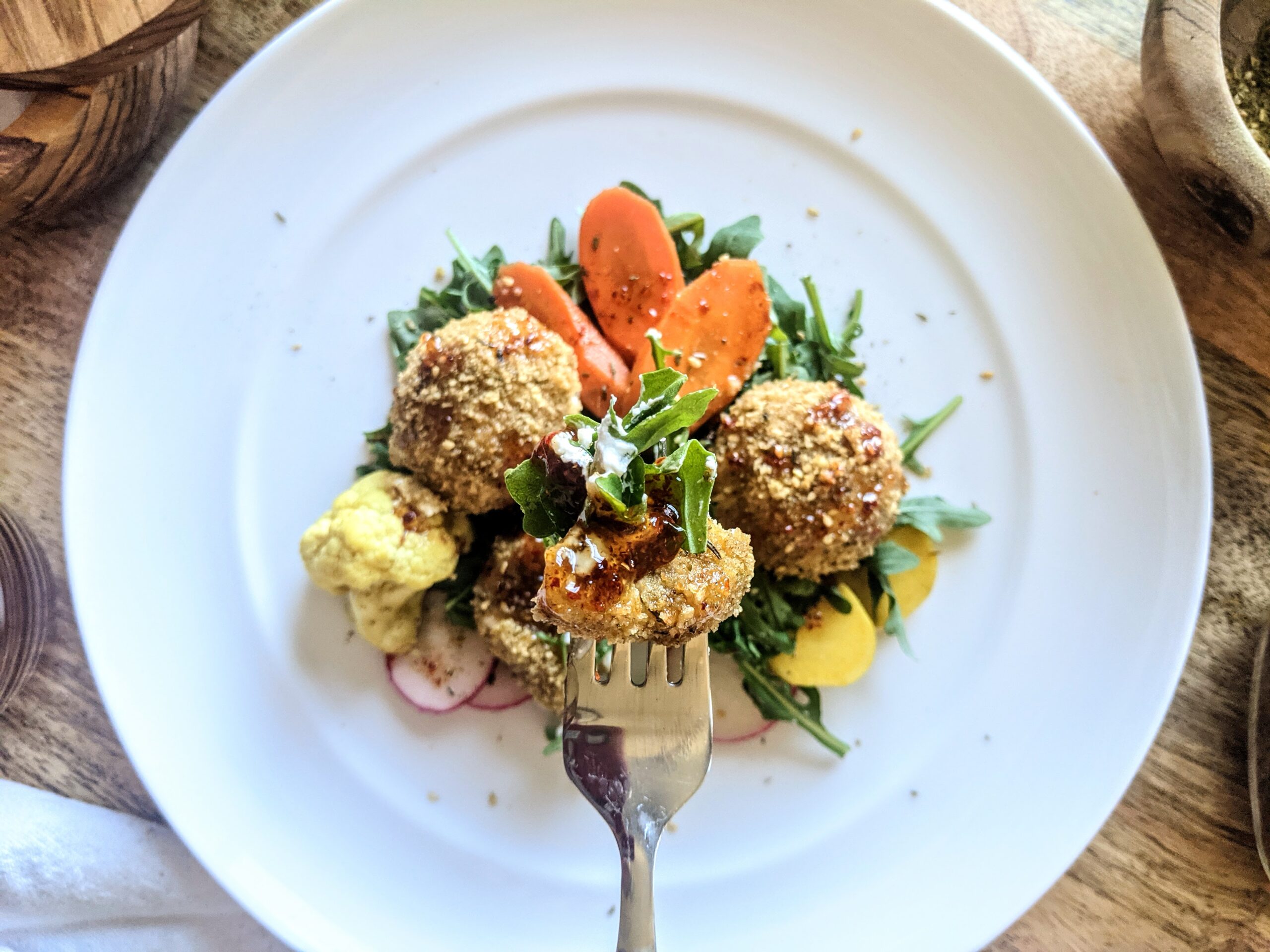A trio of walnut and za'atar crusted baked-creamy goat cheese balls. Served on top of homemade curried carrot and cauliflower pickles and wild arugula.