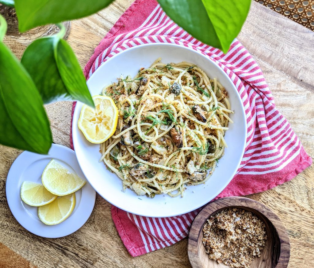 A bowl of smoked mussel spaghetti with fresh lemon, homemade breadcrumbs, and fennel fronds.