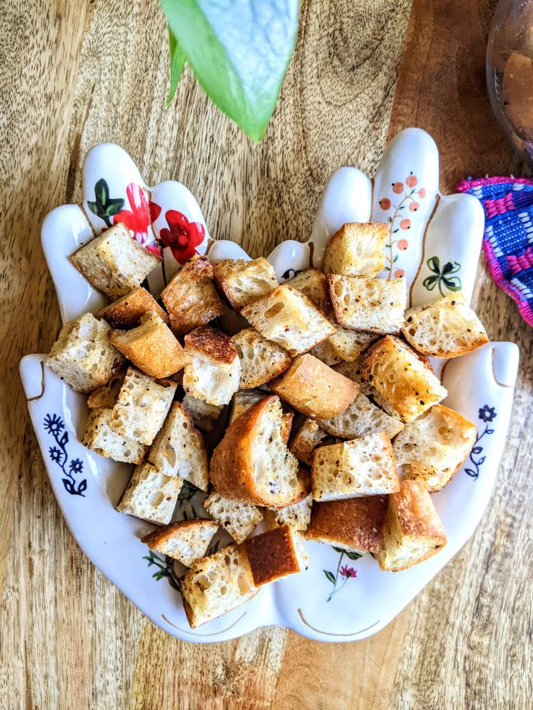 A handful of croutons on a tray shaped like a pair of open hands.