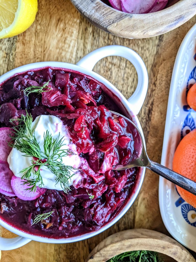 A bowl of Borscht close-up. Topped with a dollop of sour cream and fresh dill.