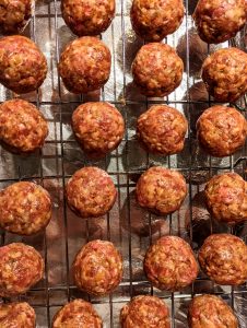 A baking rack full of freshly rolled out meatballs