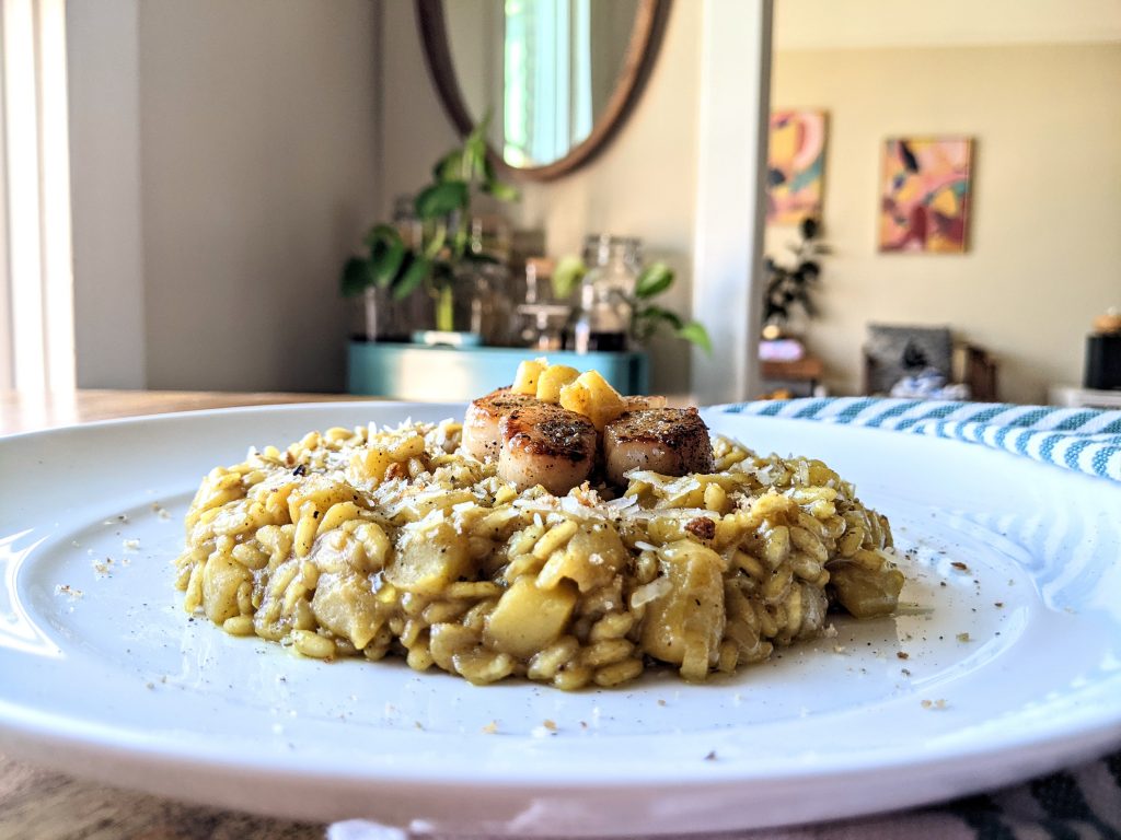 A closeup sideview of the Curried Apple Risotto with seared scallops places on top.