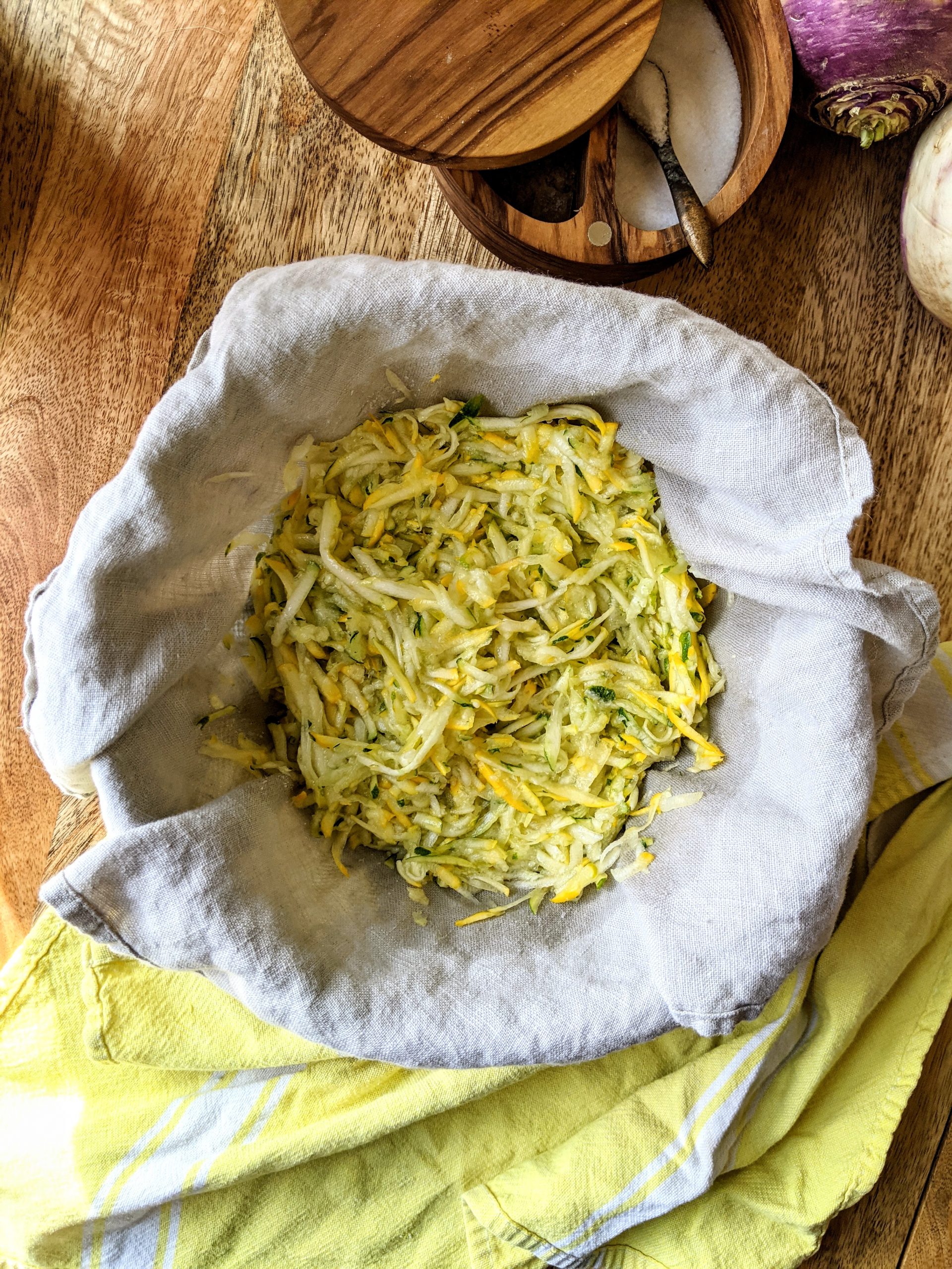 Grated zucchini in a linen napkin lined strainer.