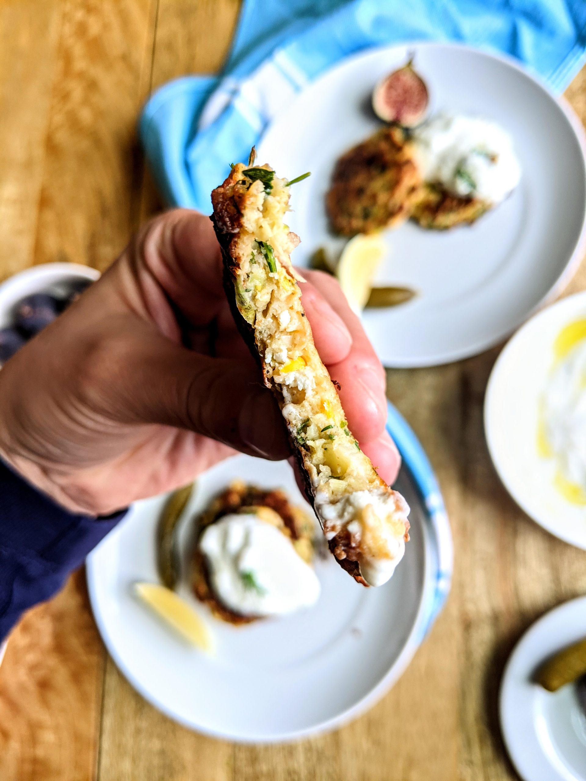 A Zucchini & Feta Fritter in a hand right after taking a bite.