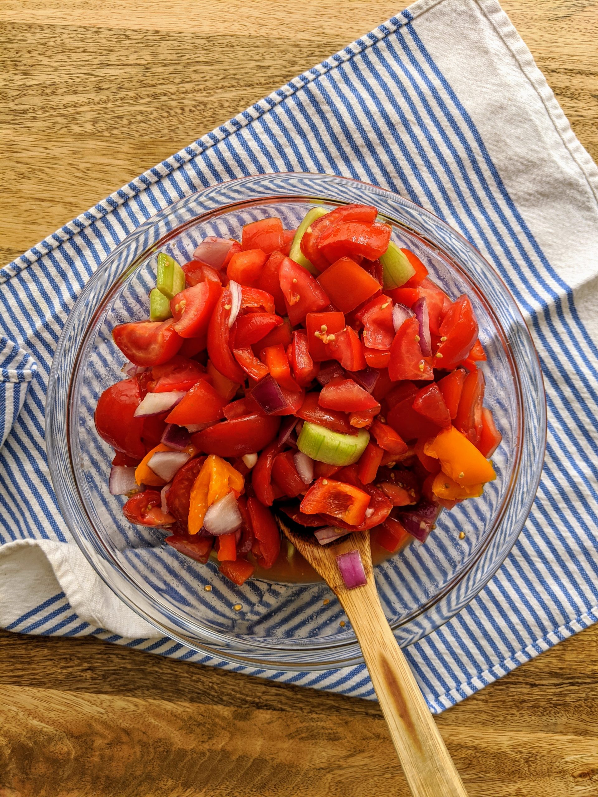 Tomatoes, cucumbers, bell pepper, and onion; mixed together in a large glass bowl.