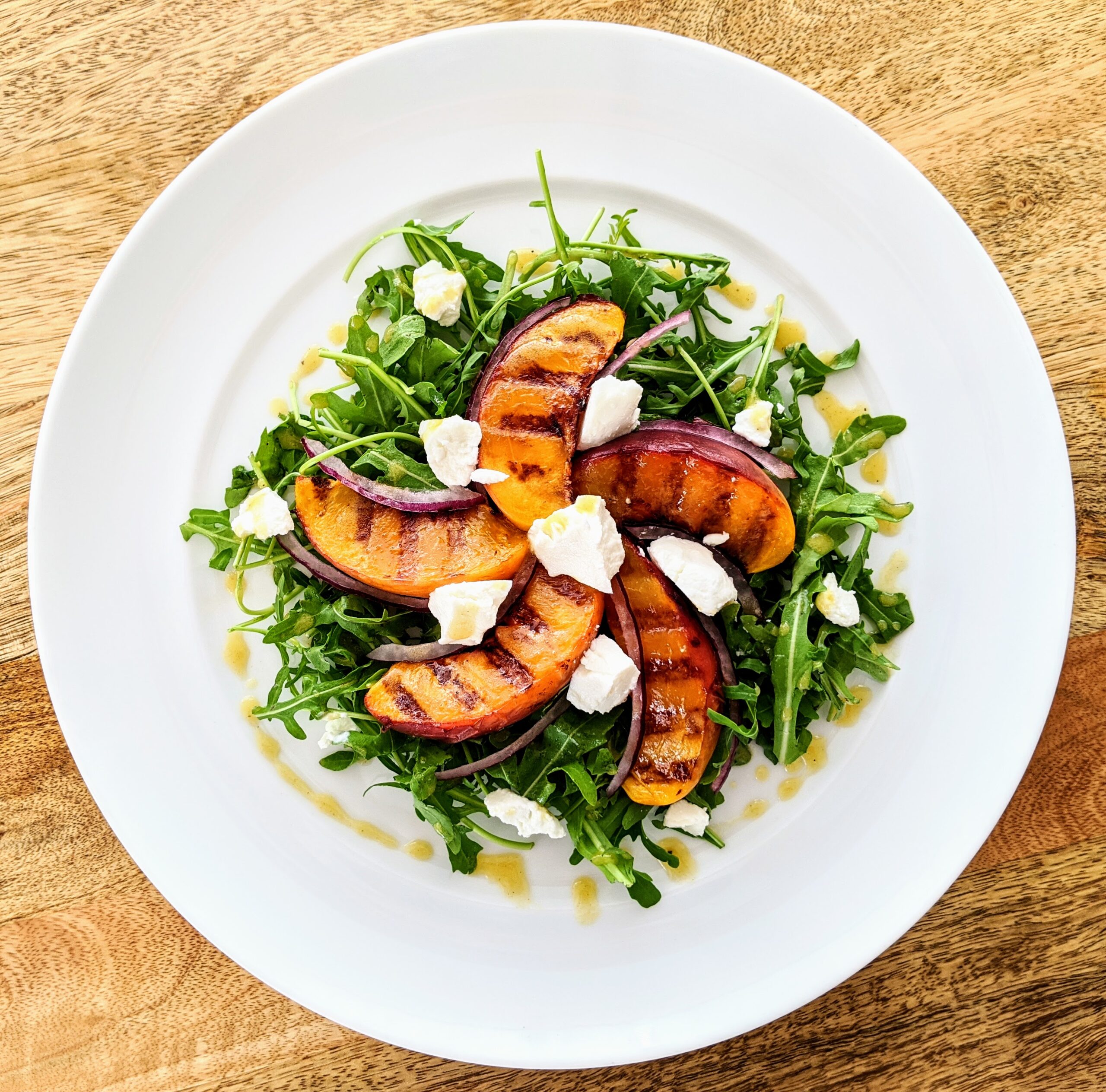 Champagne Vinaigrette drizzled on a grilled peach, arugula, and chèvre salad.