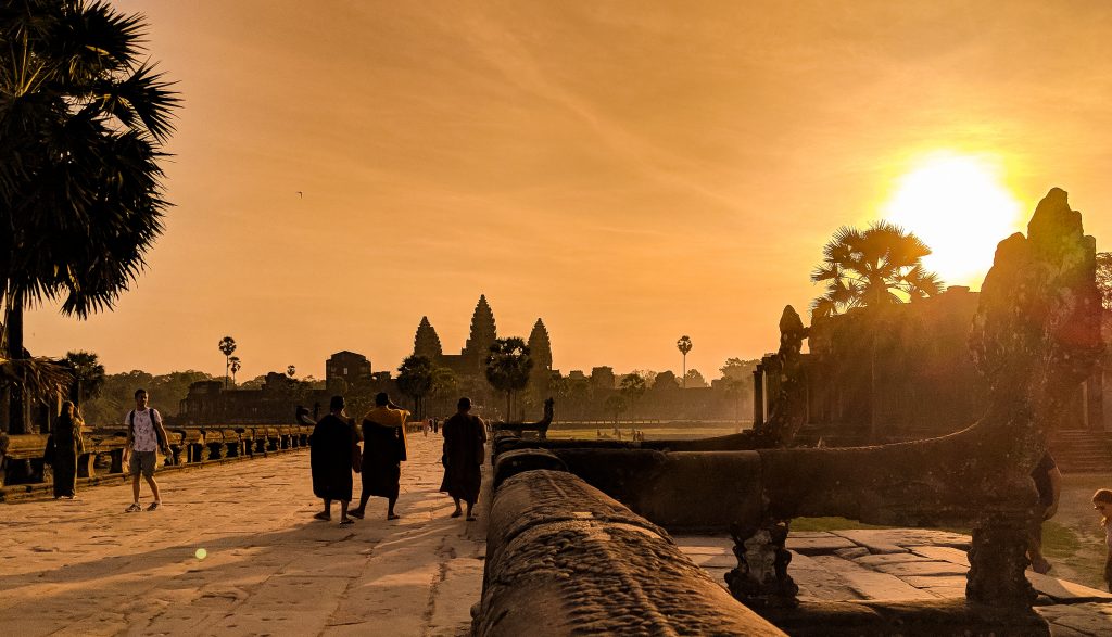 The sun rising above the Main Temple of Angkor Wat. Three monks walking towards the sun can be seen in the photo.