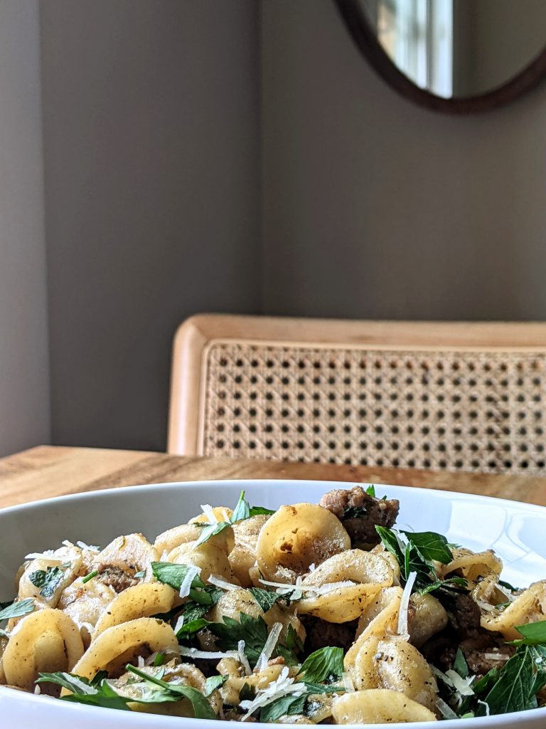 A bowl of orecchiette pasta with browned ground turkey, capers, fresh parsley, and finely grated cheese.