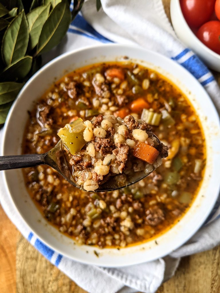 A spoonful of hearty Beef and Barley Soup. In the spoonful of soup you can see Italian barley, celery, carrot, ground beef, and a rich broth.