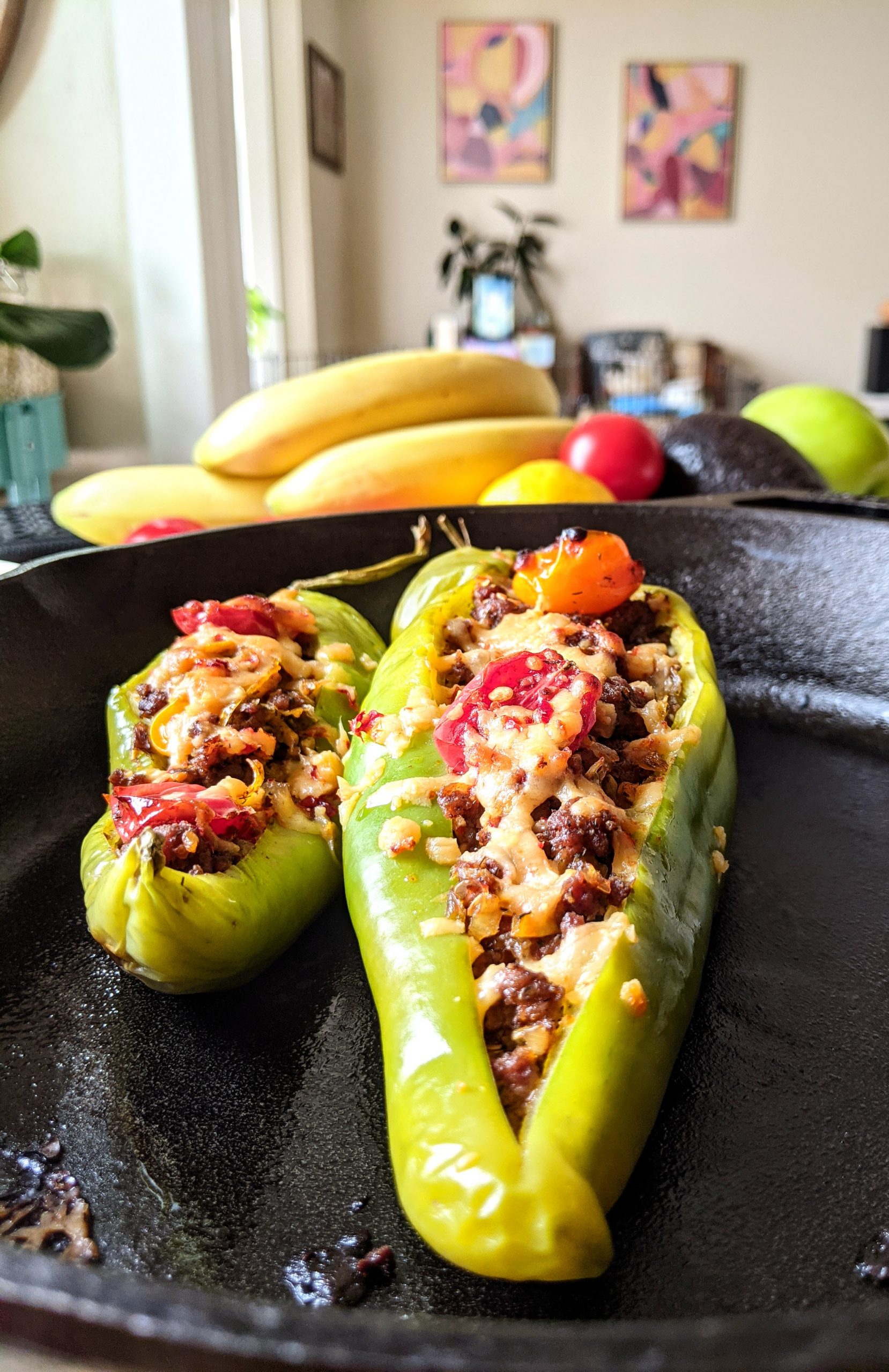 A closeup of two Georgian inspired stuffed hatch chili peppers with melted cheese.