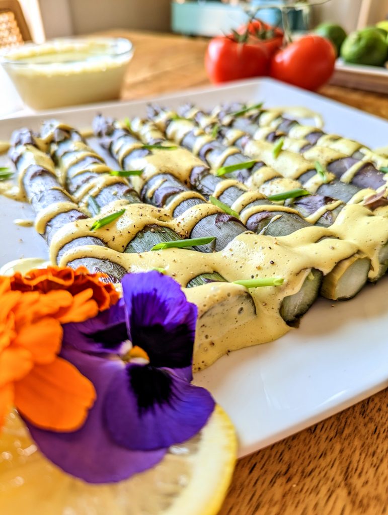A plate of steamed asparagus drizzled with tarragon and chive Hollandaise Sauce.