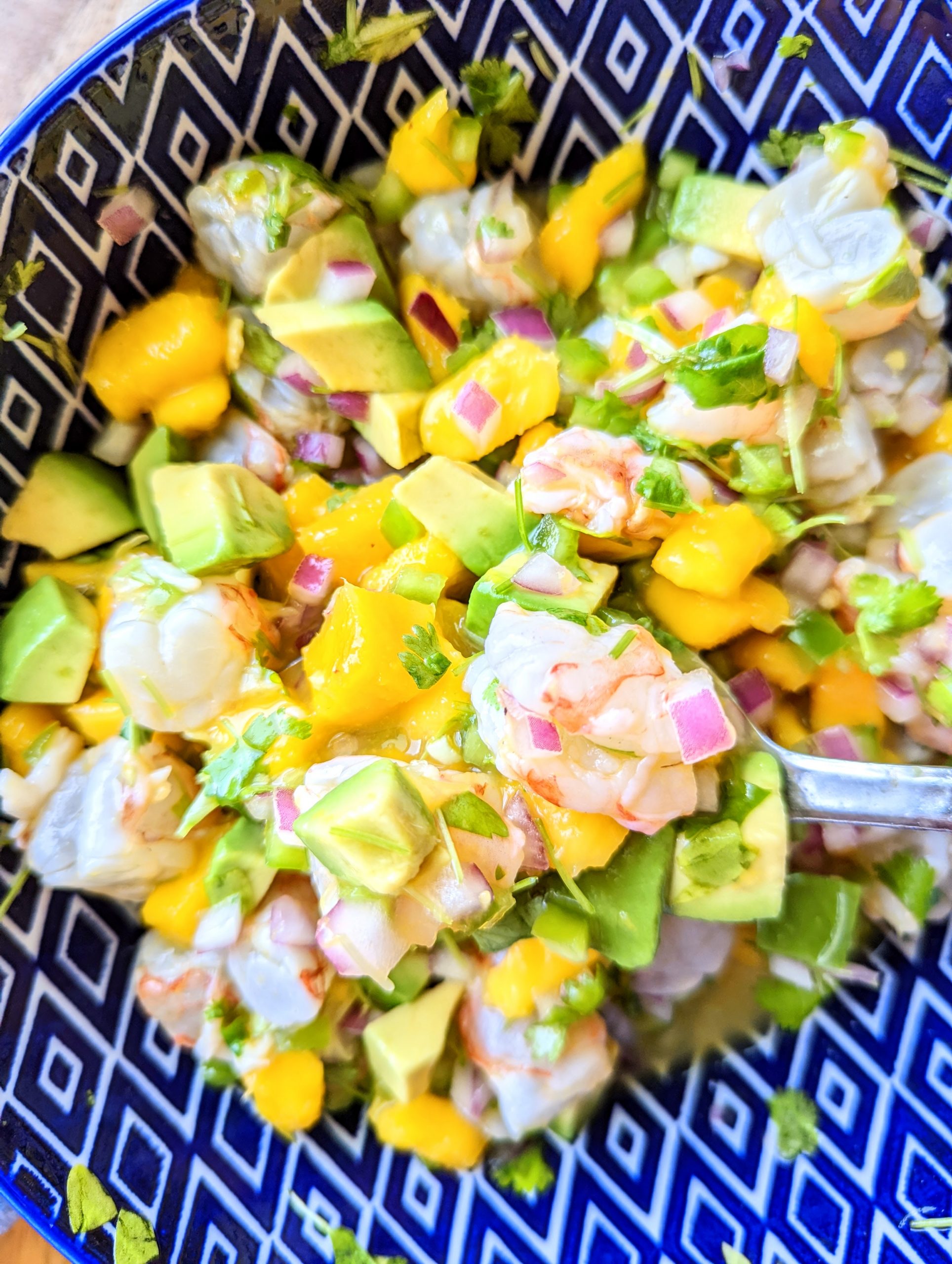A spoonful of shrimp ceviche with mango and avocado.