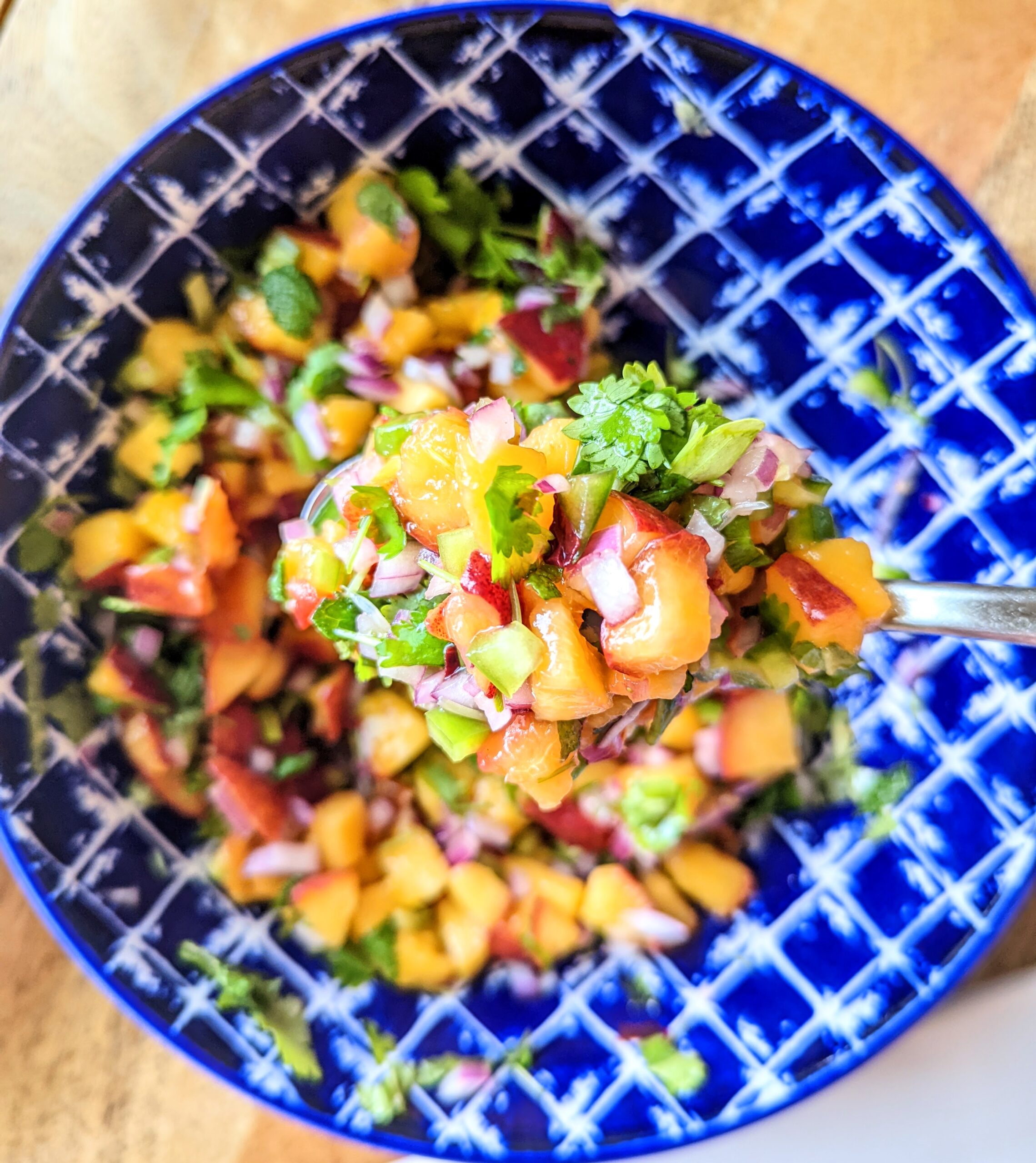 Stirring up some vibrant peach salsa in an indigo and white bowl.