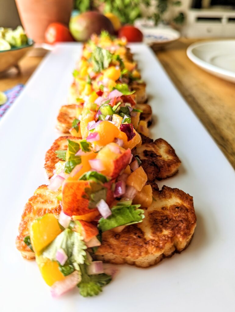 A head-on close-up table view of grilled halloumi and peach salsa.