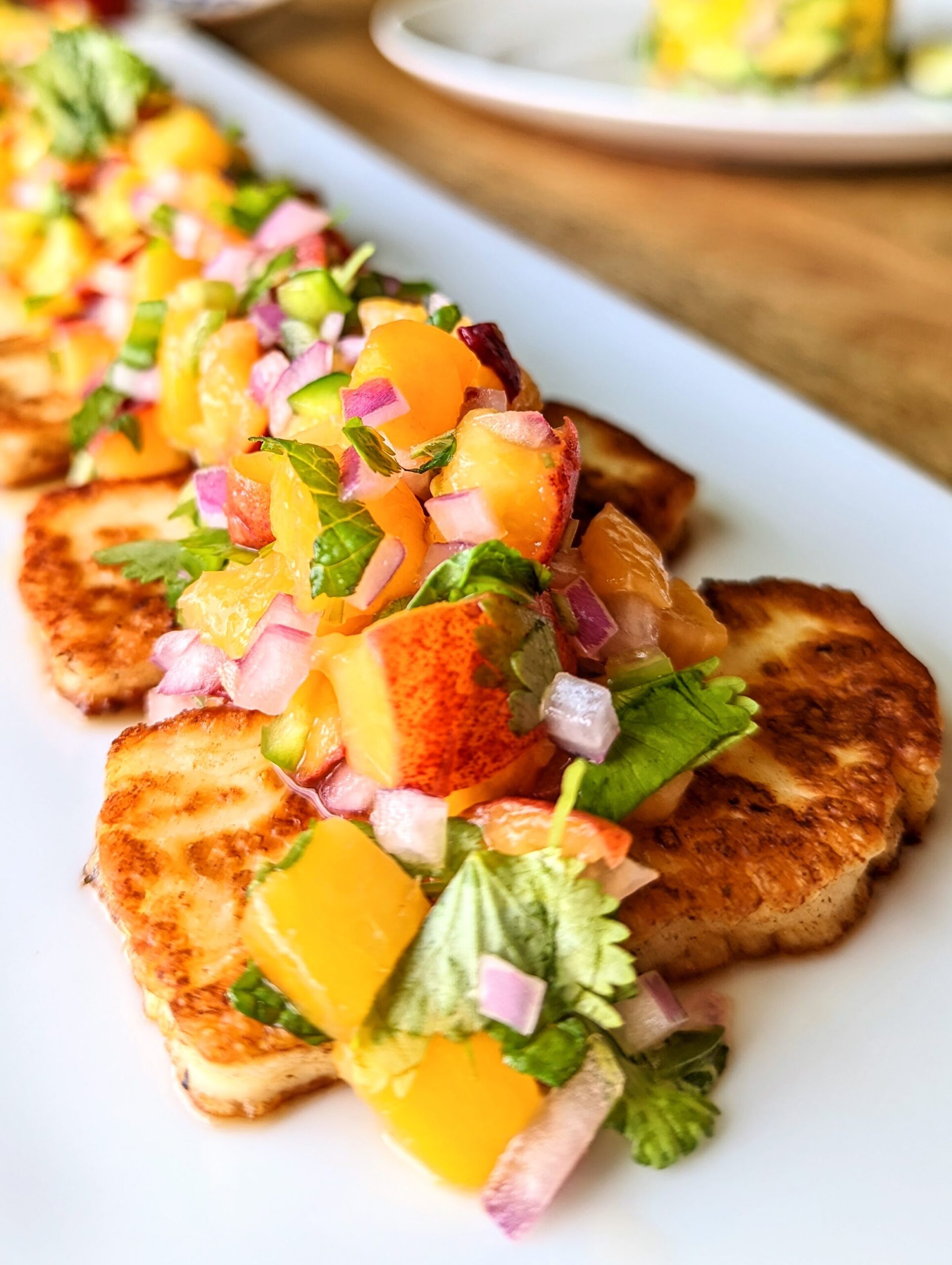 A close-up table view of grilled halloumi and peach salsa.