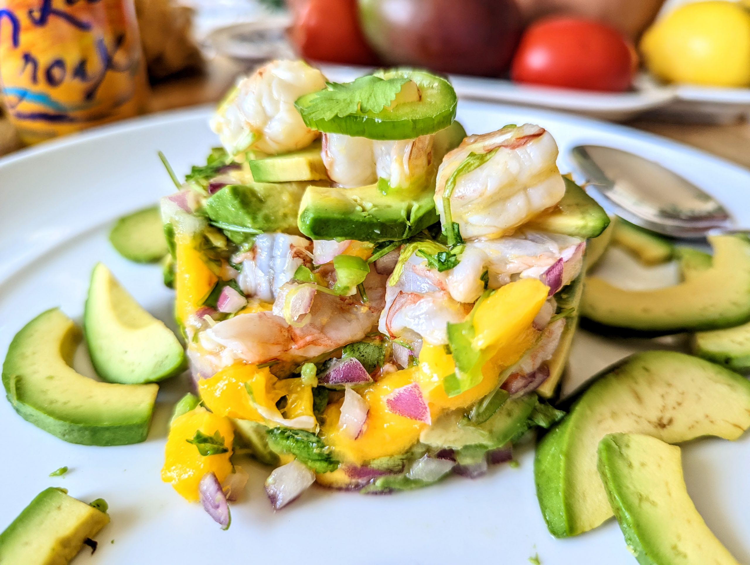 A tower of shrimp ceviche that's been cut into. Pieces of plump shrimp, mango, avocado, cilantro, and jalapeño are visible.