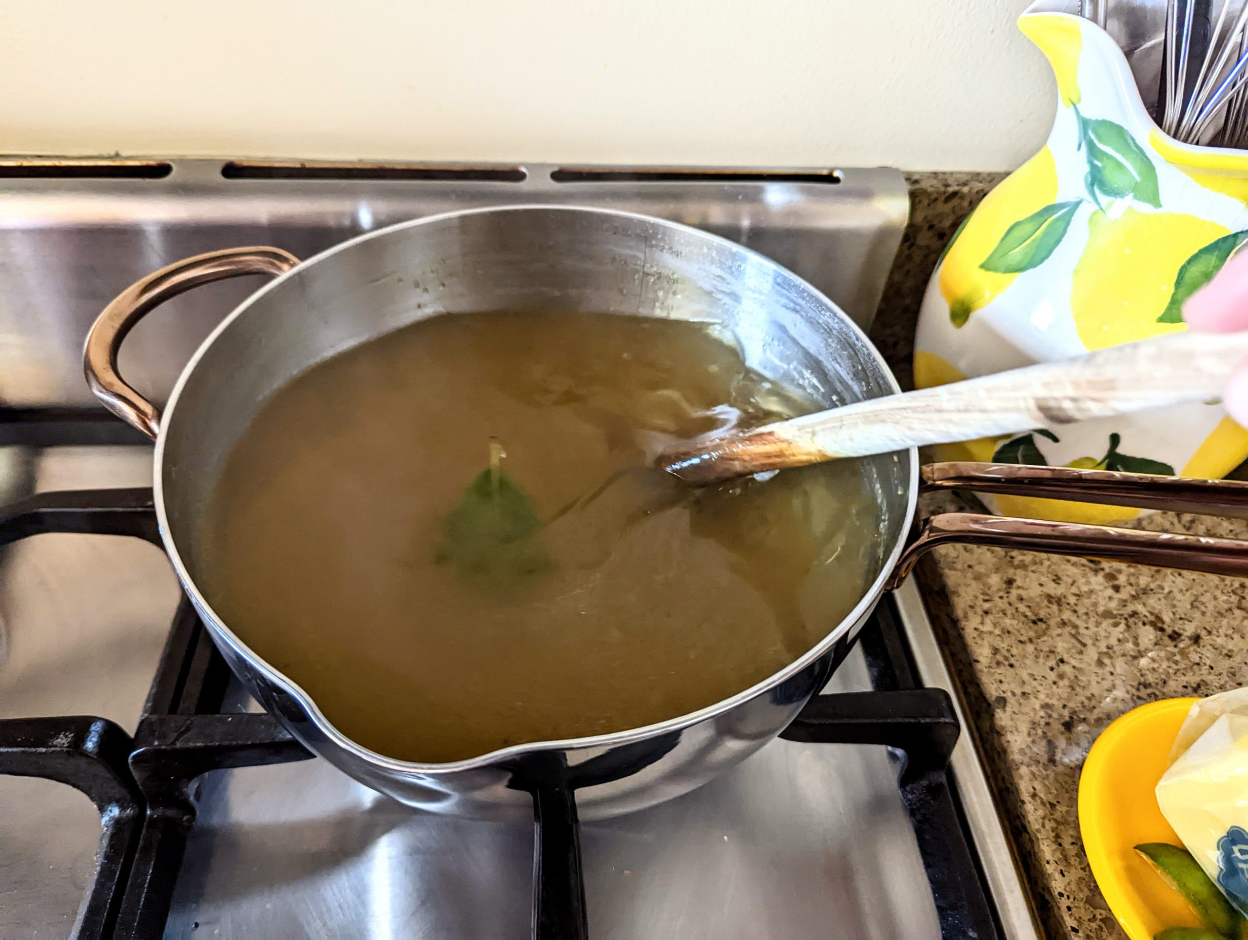 A saucepan of bay leaf infused chicken stock simmering away on the stove.