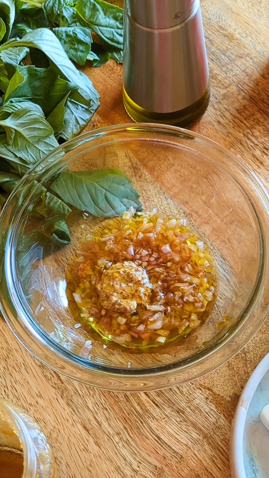 A medium-sized glass bowl with all of the ingredients for the mustard and cider vinaigrette.