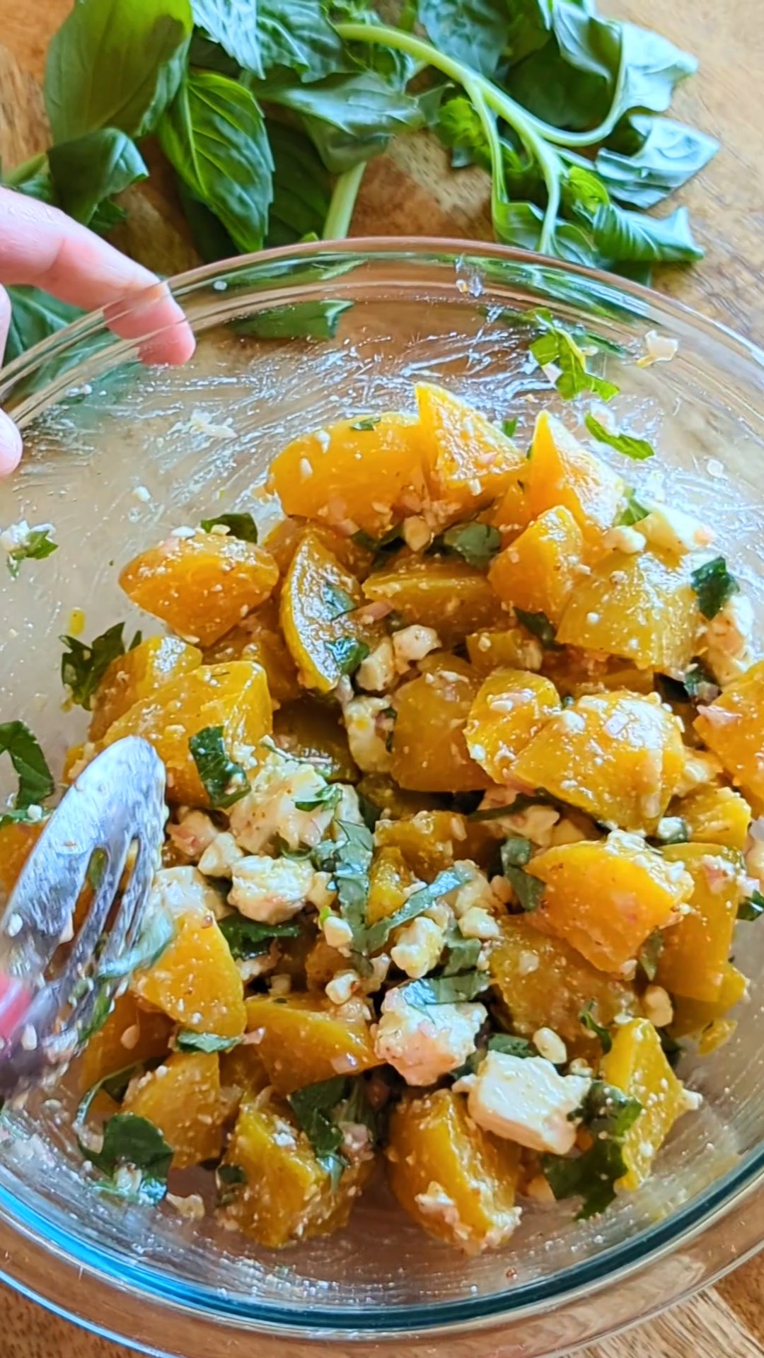 Mixing up a big glass bowl of chilled golden beet salad with feta and basil.