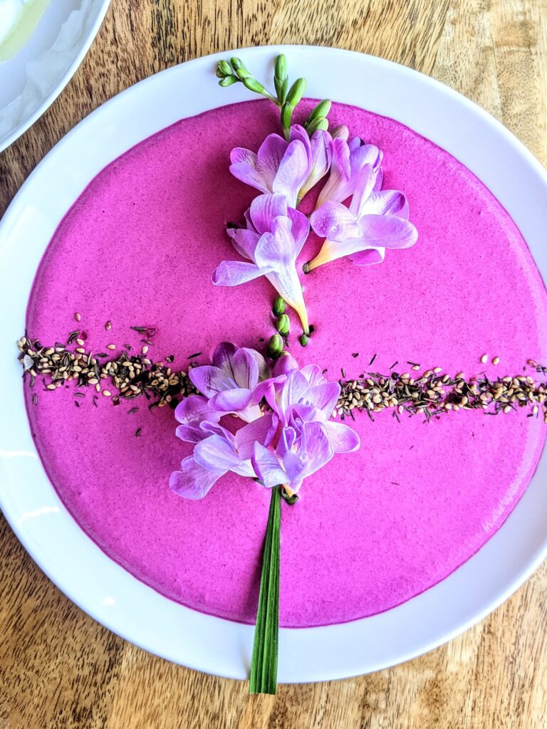 A vibrant pink beet and labneh dip. Garnished with fresh freesia and za'atar.