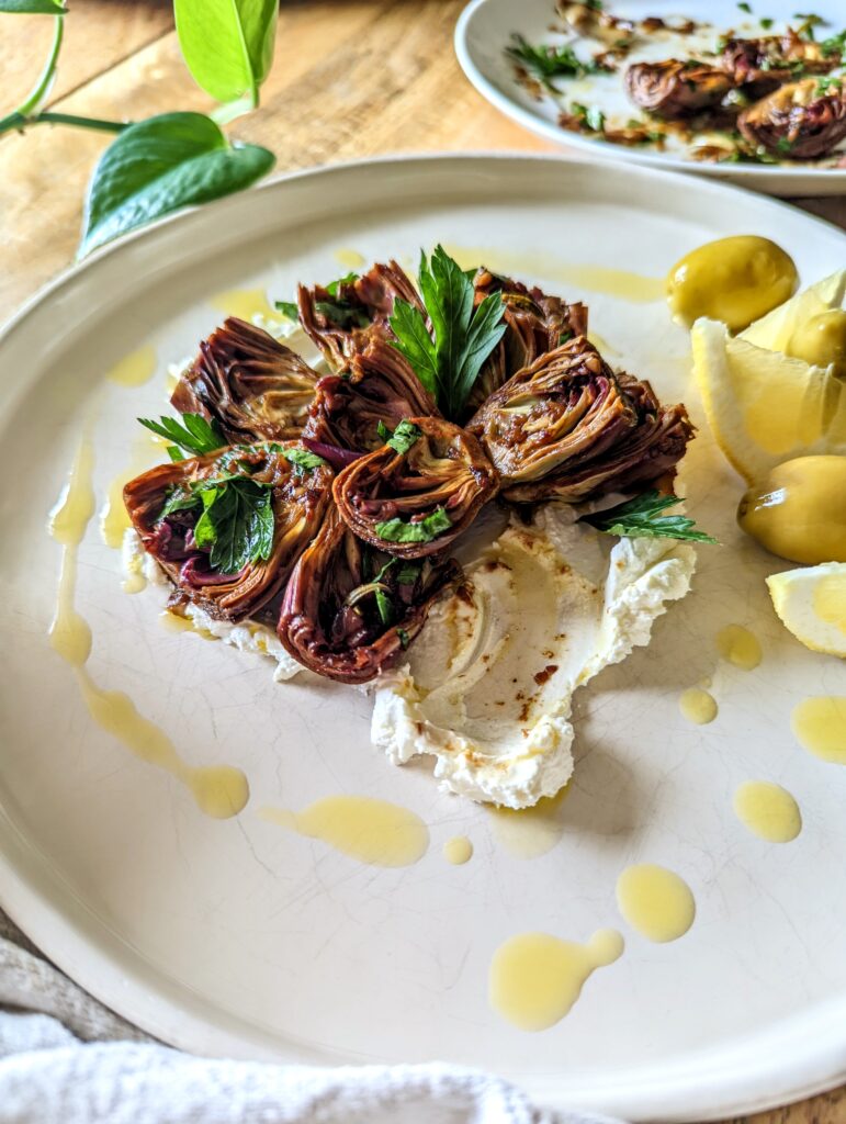 A plate of braised baby artichokes, served on a bed of homemade labneh.