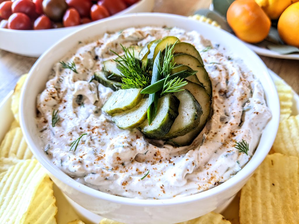 A closeup of dill pickle and chive dip, topped with homemade dill pickles.