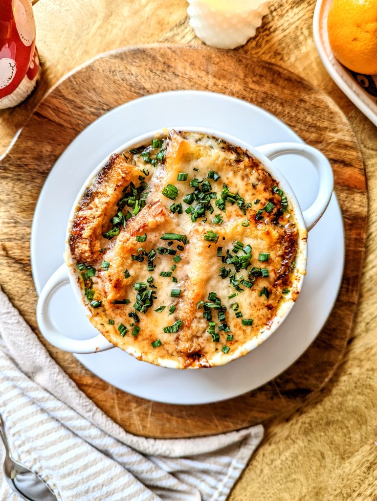 A bowl of Fresh Onion Soup topped with crispy and gooey cheese, and freshly minced chives.