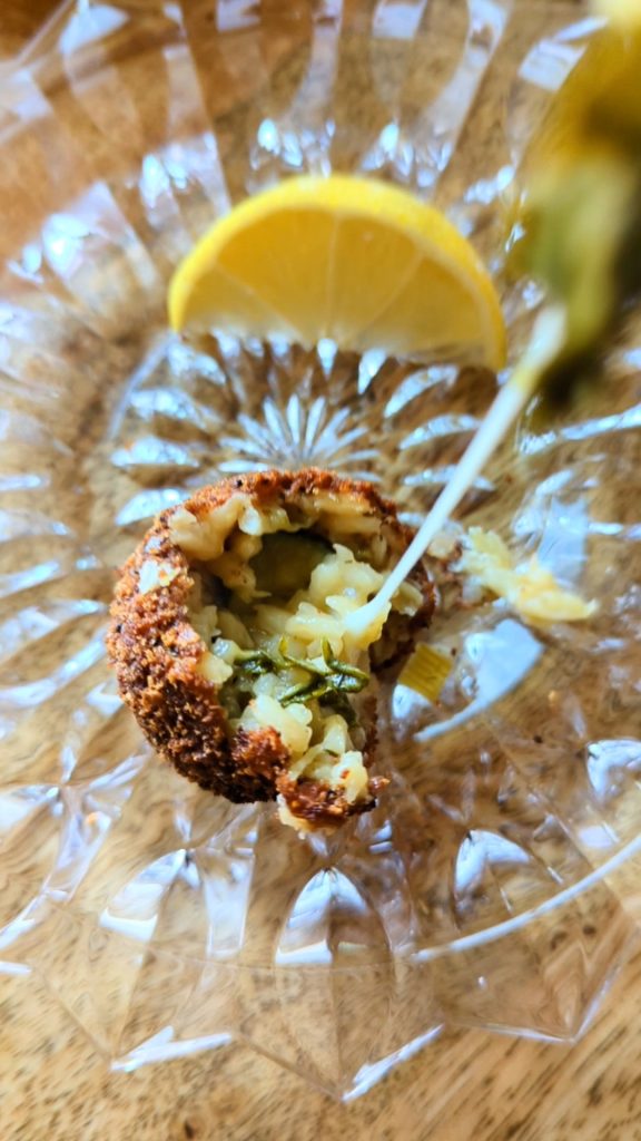 An arancini risotto ball coated in crispy homemade breadcrumbs and full of zucchini risotto and gooey melted cheese.
