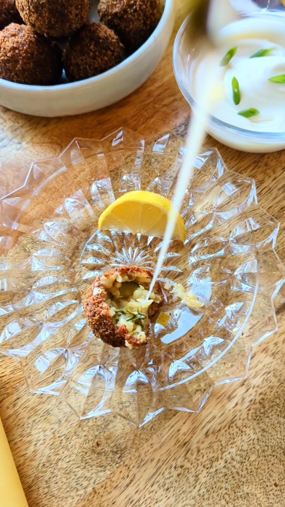 A long string of melted cheese being pulled from an arancini risotto ball.