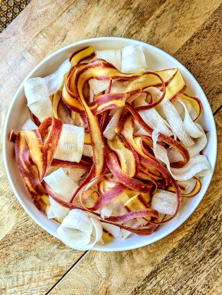 A large white plate full of multicolored carrot ribbons; orange, purple, red, and white.