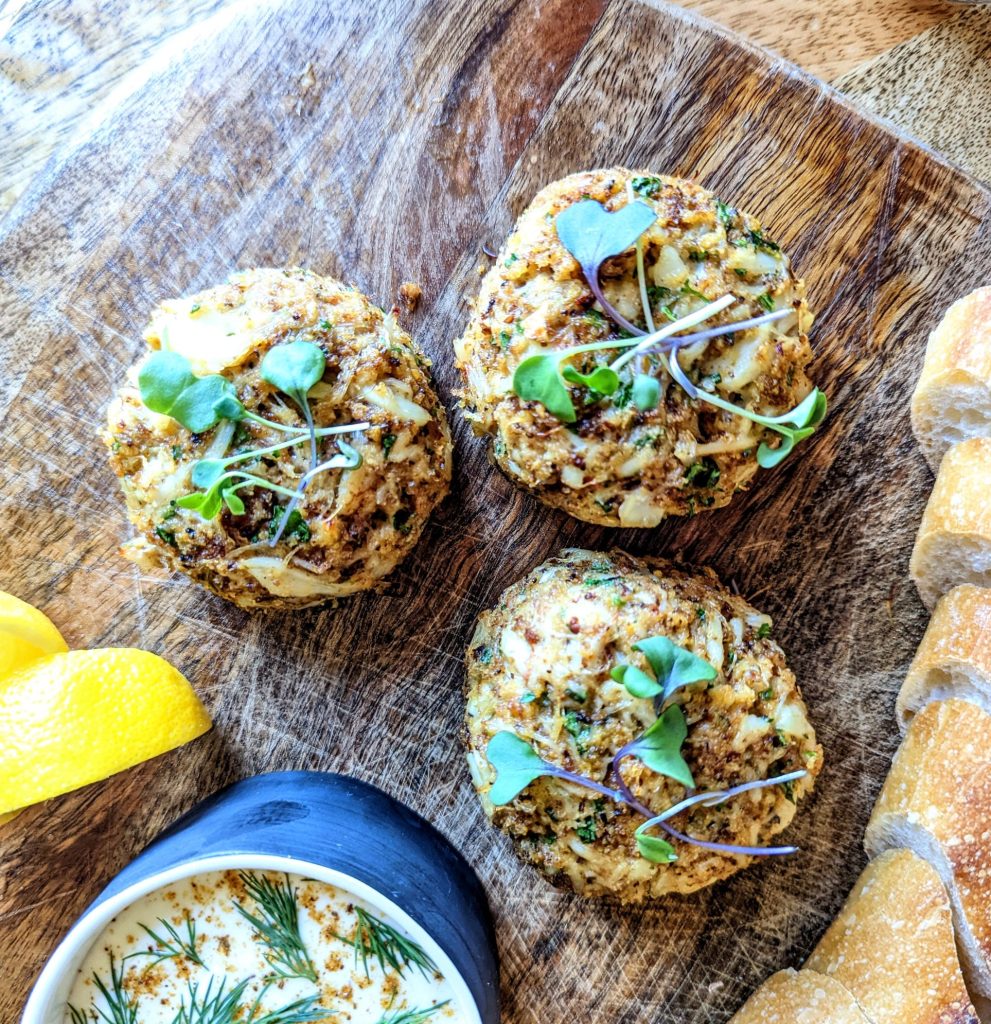 A trio of baked crab cakes topped with micro greens.