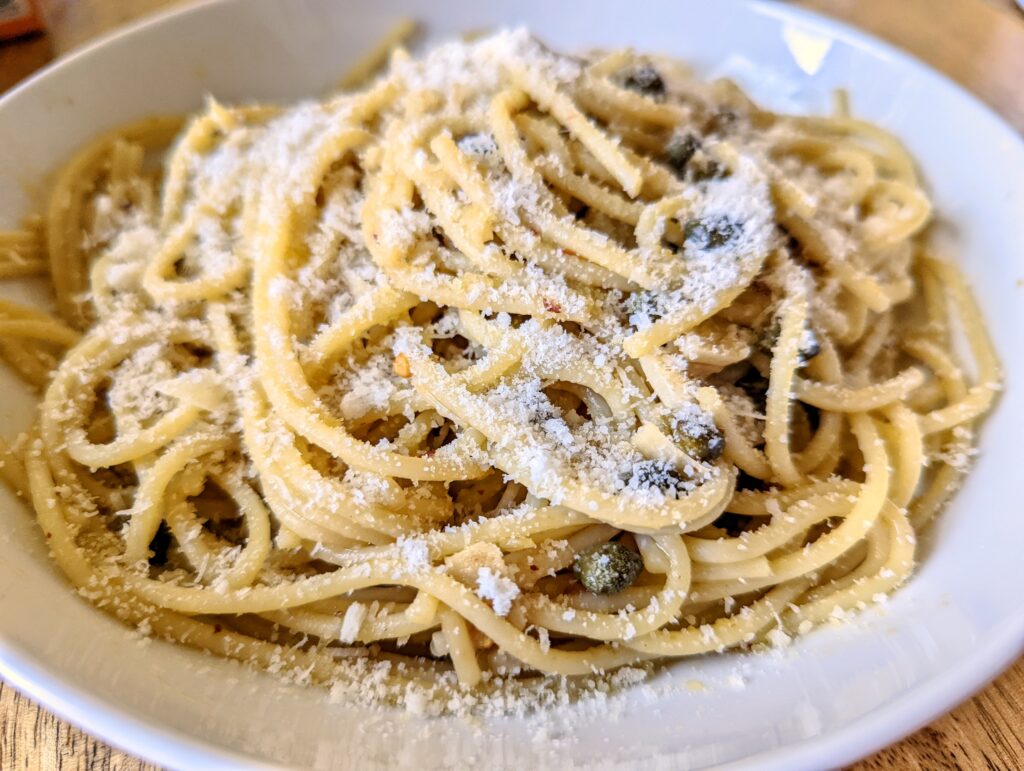 A bowl of anchovy and caper spaghetti topped with finely grated Pecorino.